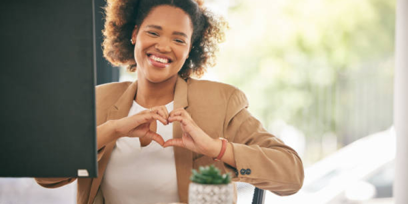 Portrait, business woman and smile with heart hands in office for care, kindness and emoji icon. Happy young black female worker with finger shape for thank you, trust and hope of support in agency
